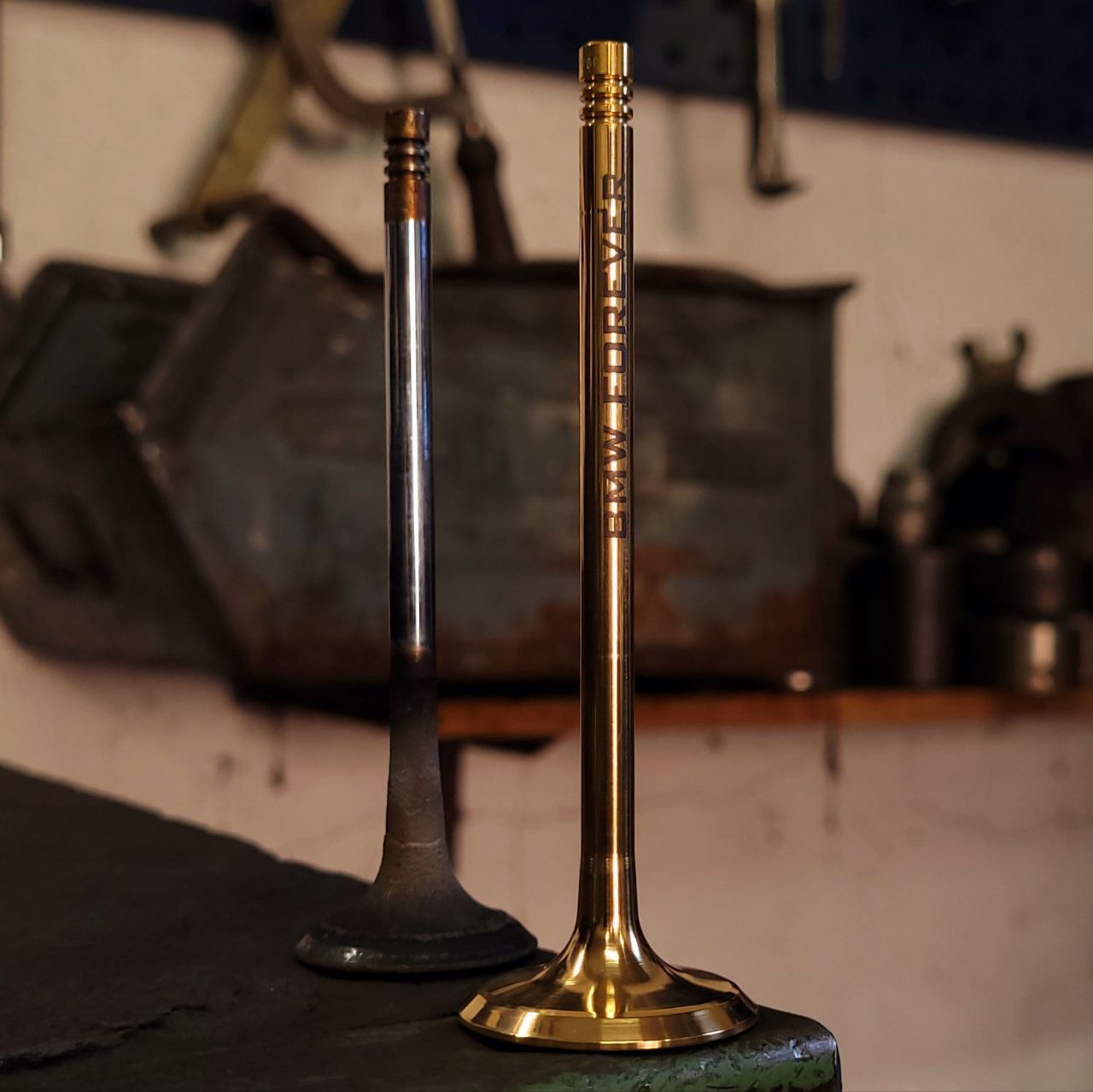 Ein außergewöhnliches Souvenir. Als Basis dient ein sorgfältig aufbereitetes Einlassventil aus einem gebrauchten M52 BMW-Motor. Das Ventil ist mit 18K vergoldet und einer Lasergravur „BMW FOREVER“ versehen. Ventil in der Garage ALT und NEU stehend abgebildet