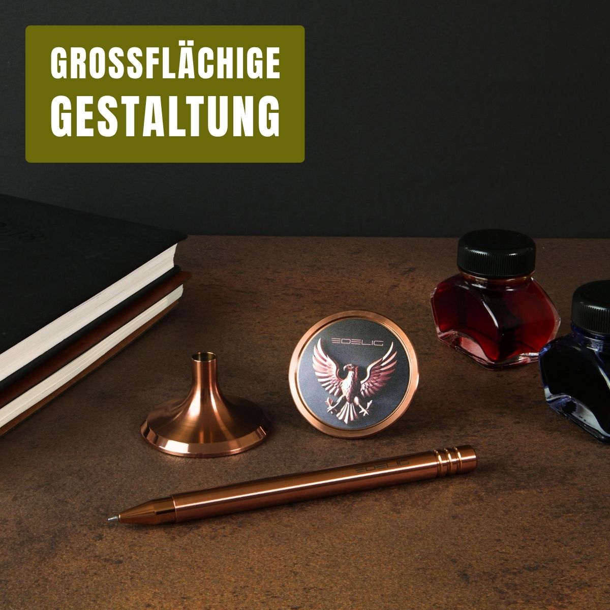 Das Bild zeigt einen exklusiven Tintenroller in PVD- Kupfer mit passender Stifthalterung und großflächig personalisiertem Ventilteller. Auf der runden Fläche ist ein detailreich graviertes Adler- Motiv mit dem Schriftzug „EDELIG“ zu sehen – ein Beispiel für die vielfältigen Möglichkeiten der V4INK- Personalisierung nach Wunsch. Daneben liegen edle Tintenfässer in Rot und Blau sowie ein Notizbuch, die die Verbindung von traditioneller Schreibkultur und moderner Ingenieurskunst unterstreichen.